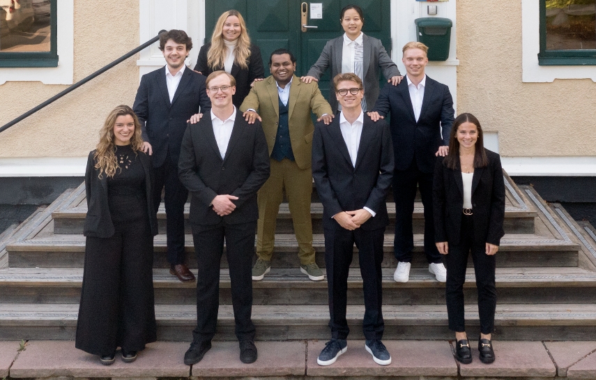 Nine persons standing in a group looking in to the camera