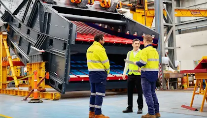 Three men talking to each other standing in an industrial environment