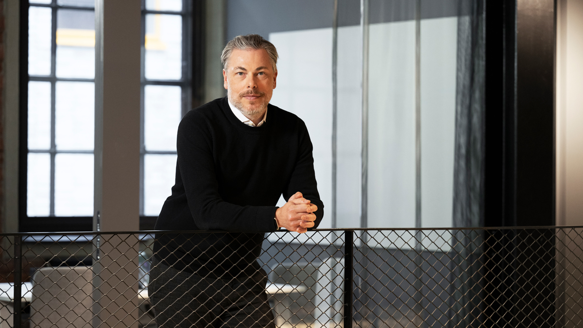 A man in his forties leaning against a railing in an office environment