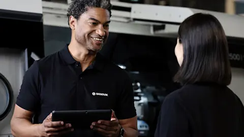 A man and a woman talking in front of a CNC machine